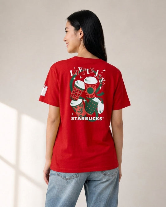Woman wearing a red Starbucks Invite Joy holiday t-shirt from behind, showing graphic print of coffee cups and white Starbucks logo