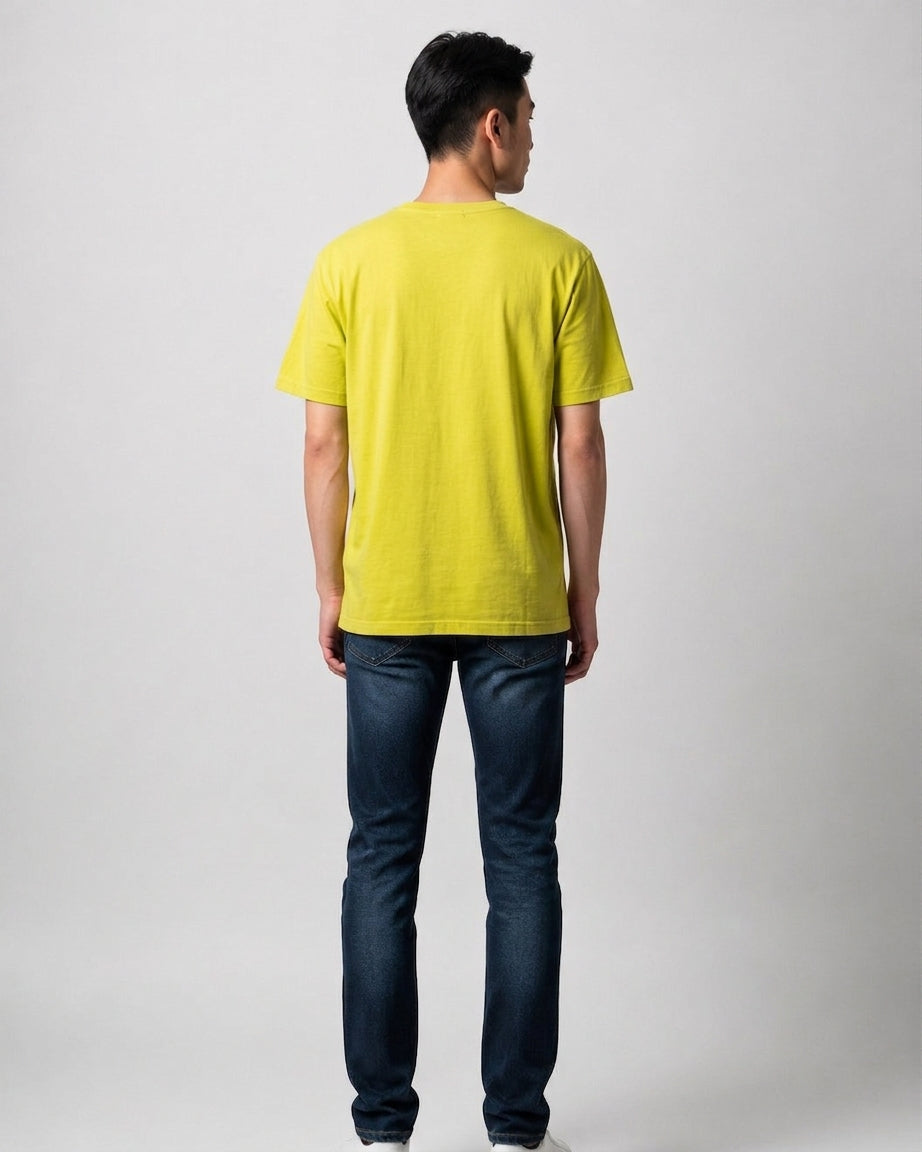 Man standing in full view from behind wearing a yellow 24 Hour Television charity t-shirt and dark blue jeans