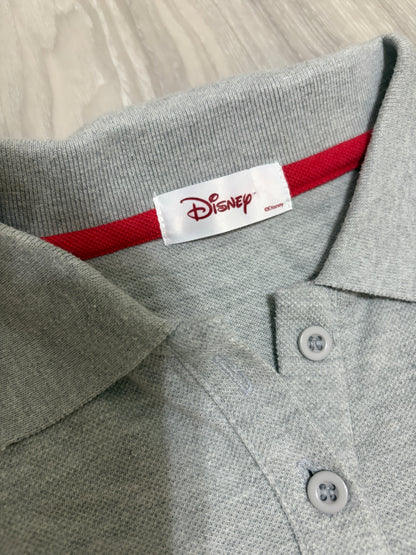 Close-up detail of the white woven Disney brand label stitched on red neck tape inside the collar of a heather grey polo shirt
