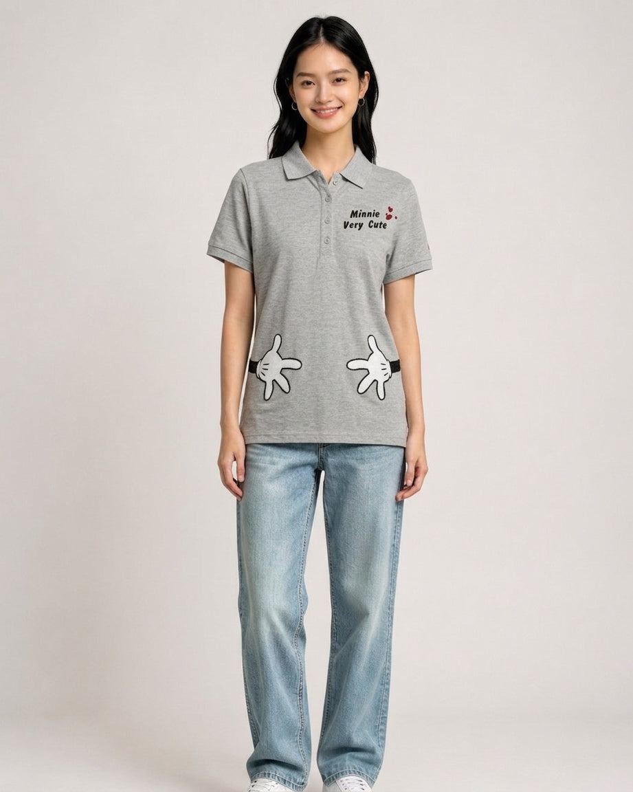 Woman wearing a heather grey Disney polo shirt featuring Minnie Very Cute embroidery and cartoon hand prints