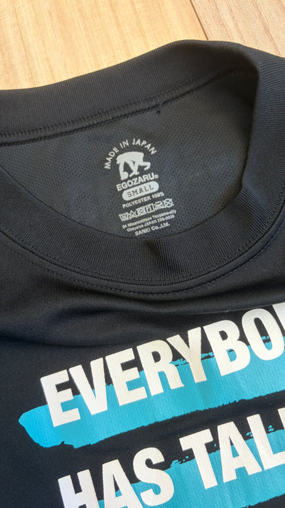 Close-up of the printed inner collar tag on a black Egozaru polyester t-shirt showing size Small, Made in Japan, and white text graphic on the chest