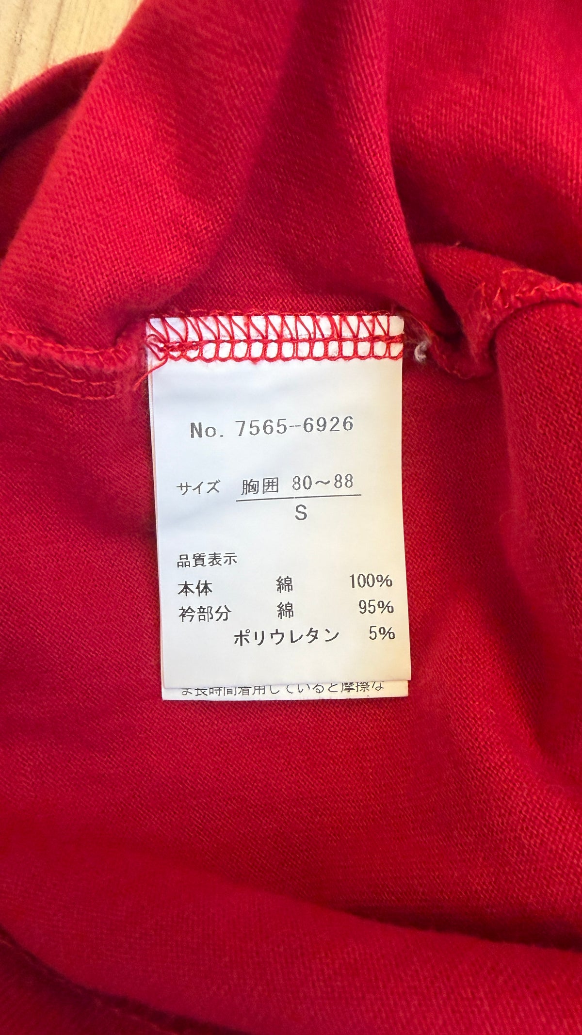 Close-up view of the inner white Japanese tag on a red Kent in Tradition VAN t-shirt displaying product number 7565-6926, size Small for chest size 80-88 cm, and material composition of 100% cotton body with 95% cotton and 5% polyurethane collar trim