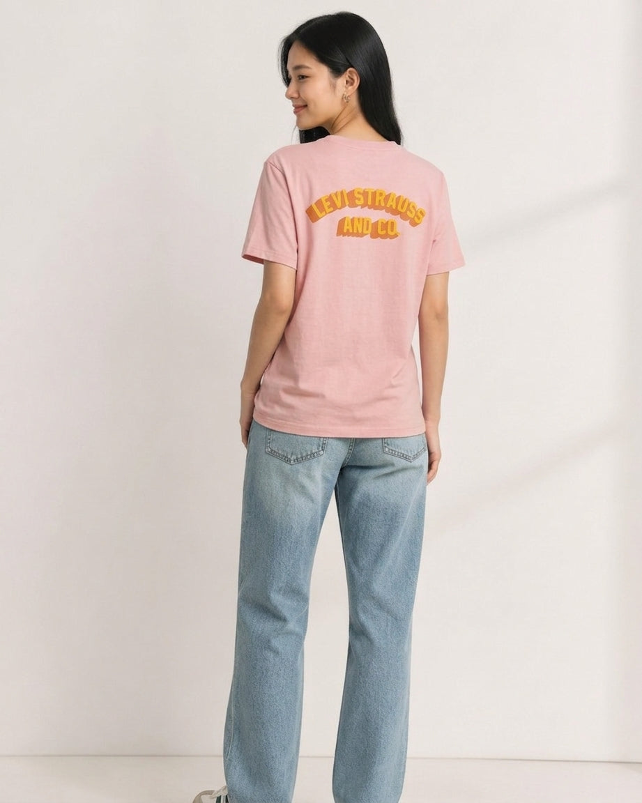 Woman wearing dusty pink Levi Strauss and Co. t-shirt showing yellow arch logo on the back, paired with light denim jeans