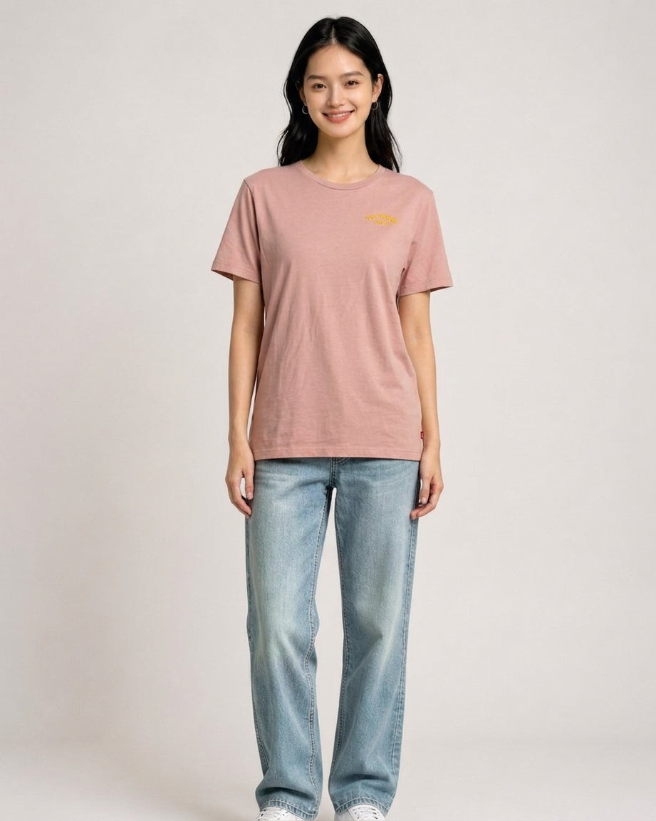 Woman wearing dusty pink Levi Strauss and Co. t-shirt showing small chest logo from the front, standing in light denim jeans