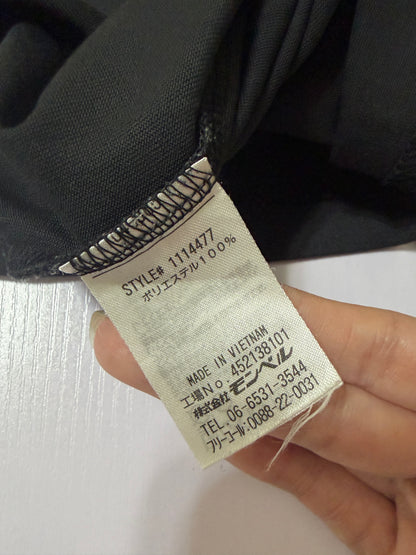 Close-up detail of the inner white care label showing style number 1114477, 100% polyester fabric composition, and Made in Vietnam on a black Montbell t-shirt