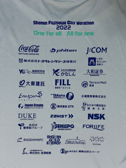 A close-up of a white athletic t-shirt printed with the Shonan Fujisawa City Marathon 2022 logo and numerous sponsor logos in blue and green text.