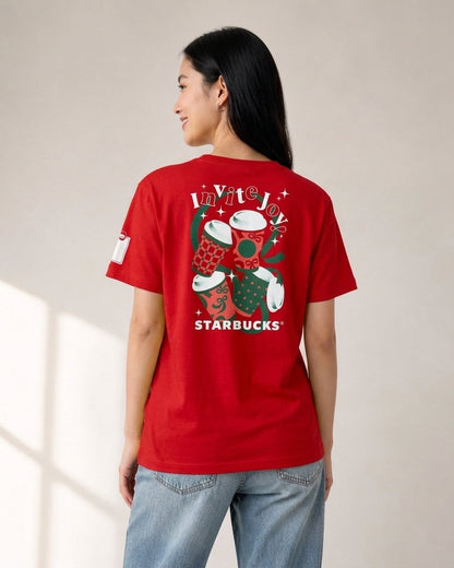 Woman wearing a red Starbucks Invite Joy holiday t-shirt from behind, showing graphic print of coffee cups and white Starbucks logo
