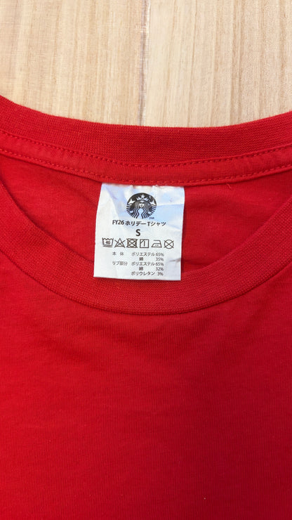 Close-up detail of the white Starbucks Siren logo inner neck label and size S care tag on a red holiday t-shirt