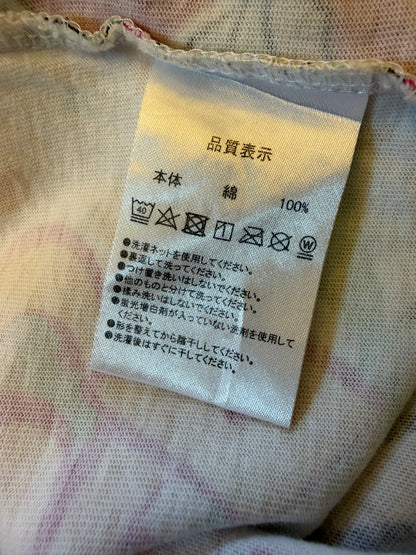 Close-up view of the inner white fabric tag on a graphic t-shirt showing 100% cotton material composition and Japanese laundry care instructions