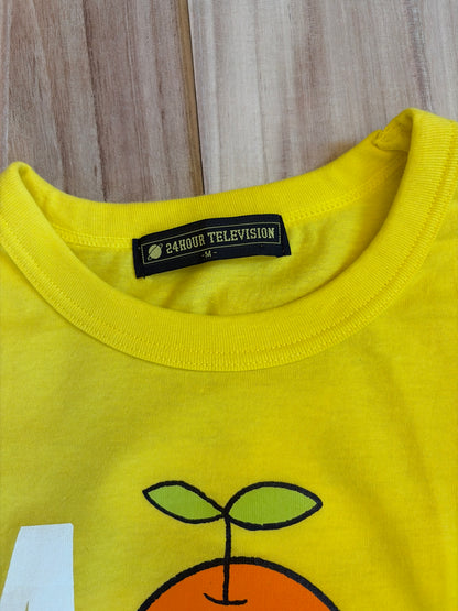 Close-up view of the inner neck collar on a bright yellow t-shirt displaying a black woven brand label reading 24HOUR TELEVISION in white block text above size M
